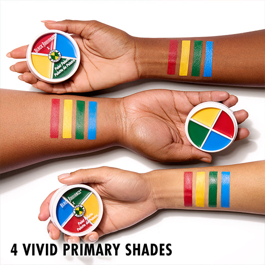 Three arms with different skin tones showing swatches of red, yellow, green, and blue from the Black Radiance x Cross Colours Paint Palette.