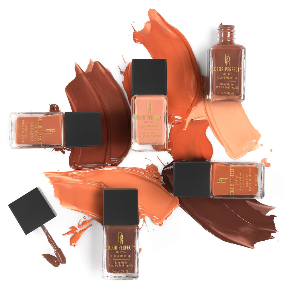 Flat lay of six bottles of Color Perfect oil-free liquid makeup in various shades, with swatches smeared across a white background